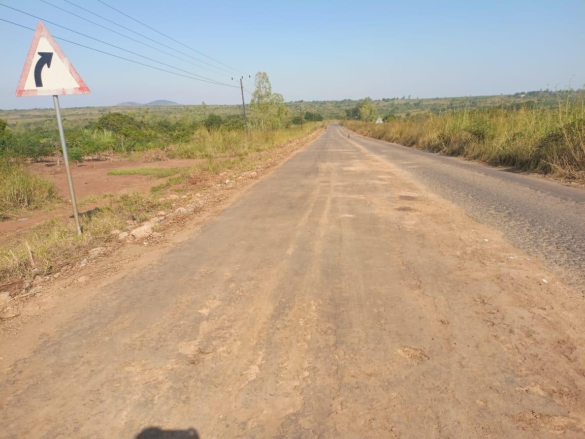 Estrada concluída em zona rural com sinal de curva à direita