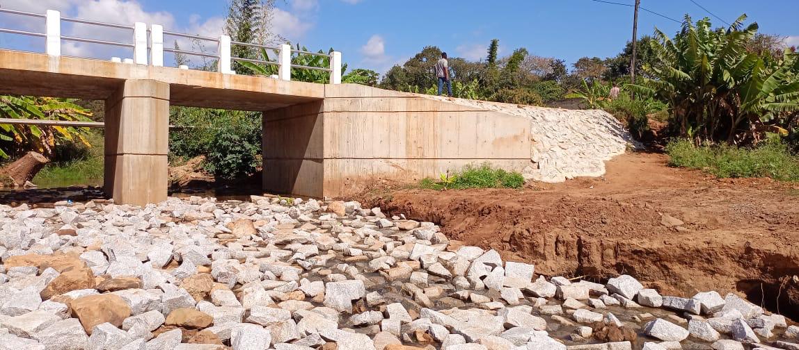 Ponte de betão concluída com guardas brancas e talude revestido a pedra