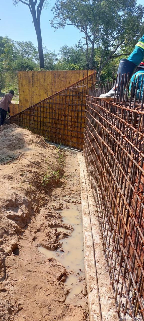 Armadura de aço numa vala de fundação com cofragem amarela ao lado