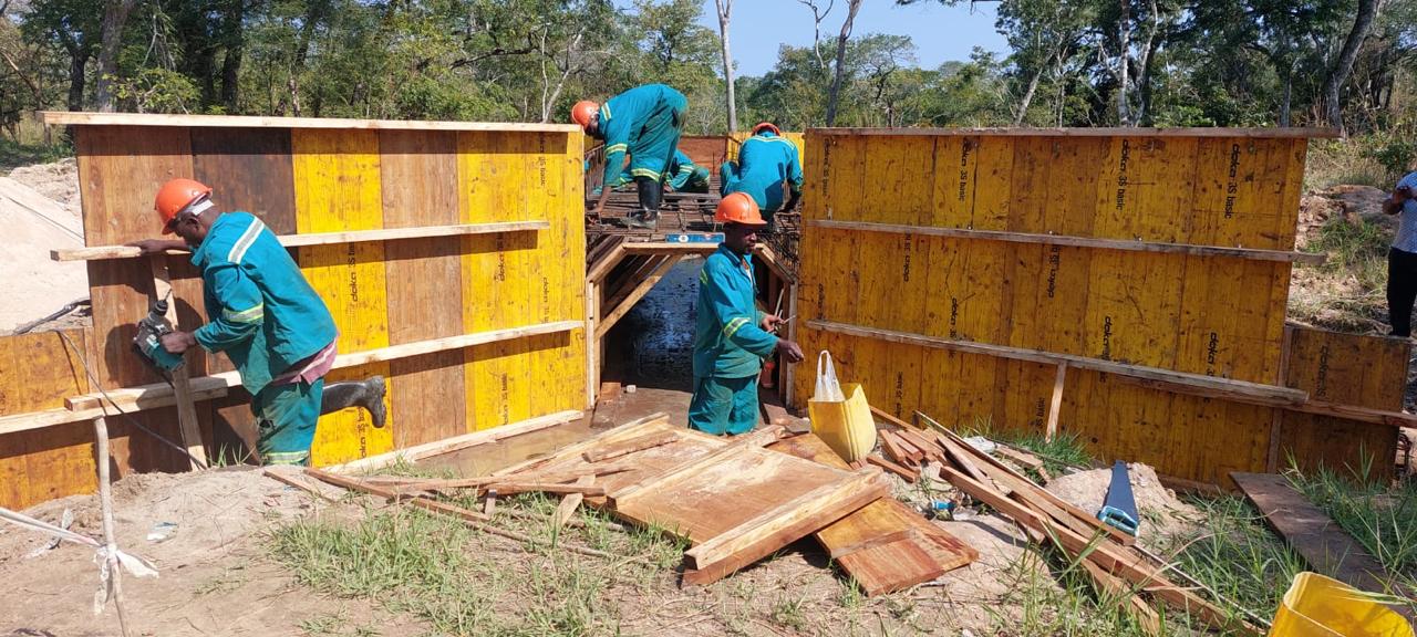 Trabalhadores de fardamento verde a montar painéis de cofragem em obra
