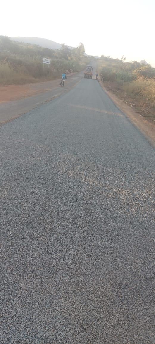 Estrada rural reabilitada com motociclista e máquina ao fundo