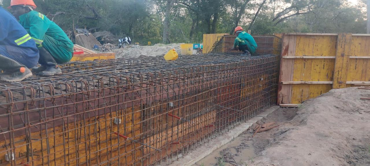 Muro em armadura de aço com cofragem escorada e trabalhadores em obra