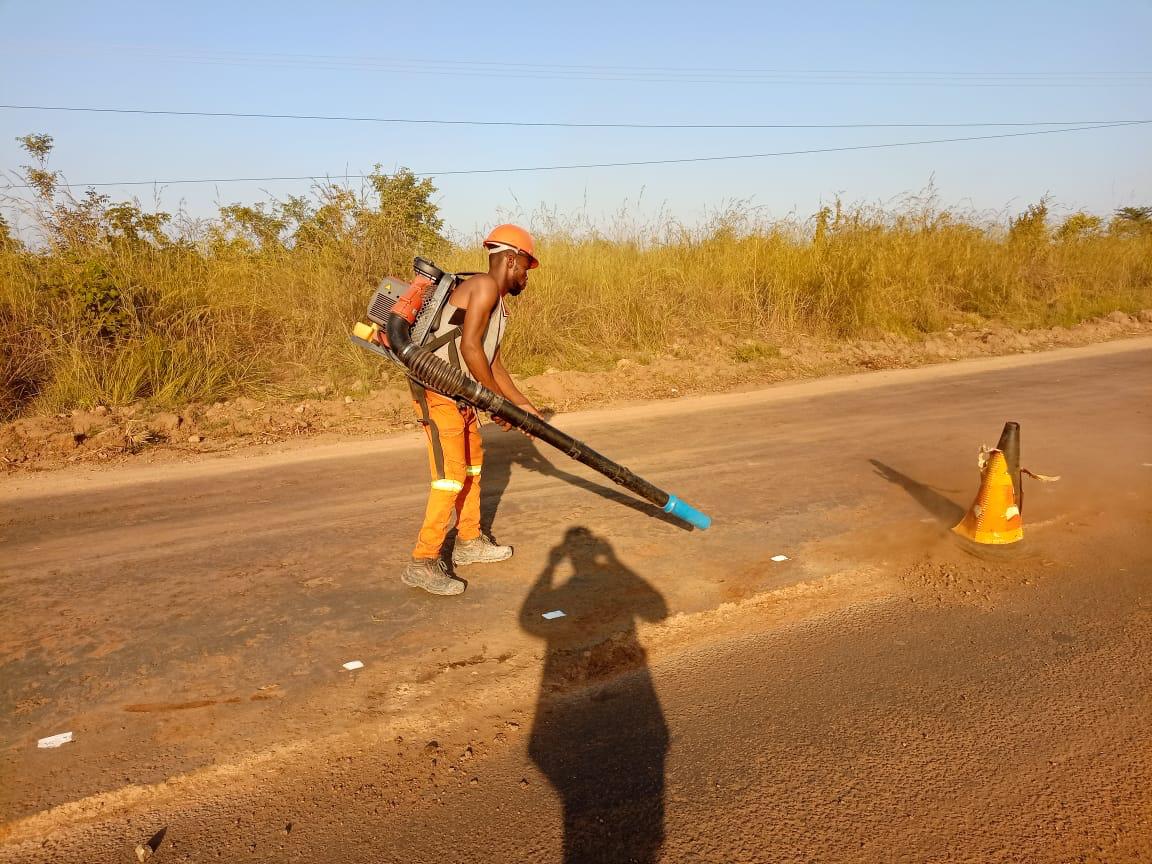 Trabalhador a limpar a faixa de rodagem com soprador antes da pavimentação