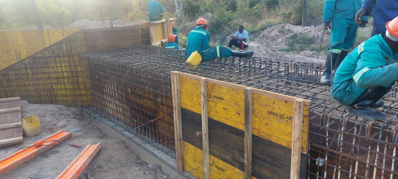 Trabalhadores a montar armadura e cofragem amarela de uma laje em betão