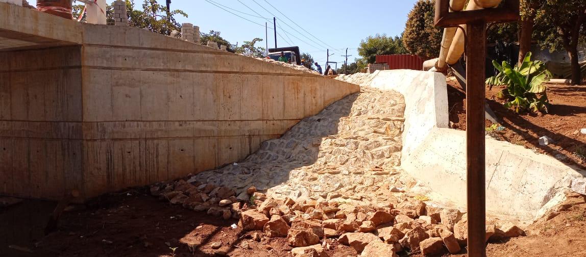 Muro de betão com revestimento em pedra arrumada e canal de drenagem